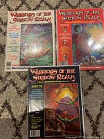 Three Warriors of the Shadow Realm comics issues 11,12,13 displayed on carpet. All three are bagged and boarded, showing vibrant cover art.