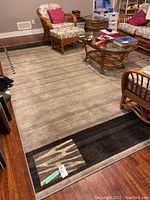 Full view of the rectangular Moonlight area rug with gradient beige to dark tones and geometric accents, showing placement under rattan furniture