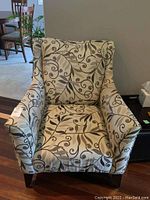 Front view of armchair showing patterned upholstery and wood legs.
