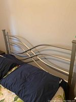 Bed frame showing curved metal bars and brushed nickel finish