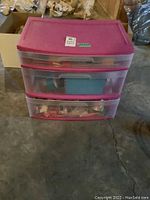 Full view of pink lidded plastic three-drawer storage unit containing crafting supplies