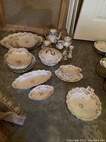 Overview photo showing all Limoges china servingware pieces arranged on floor including platters, tureen, bowls, gravy boat, shakers, creamer, sugar bowls, teapot, and egg cup