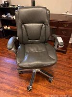 Front view of grey faux leather office chair showing damage on seat, padded armrests, and backrest