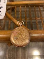 Closed hunter case front with floral engraving on gold-tone metal