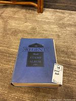 Photo of the closed blue hardcover stamp album titled 'The Regent World Stamp Album'.