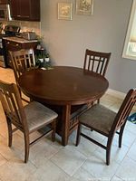 Full view of round wood dining table with four matching chairs showing their style and set appearance.