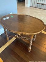 Wood occasional table, oval top with decorative edges and twist legs, visible wear and scratches on the base.