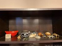 Full view of the shelf with all turtle figurines, red basket, and the Hoselton mark base.