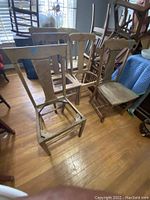 Photo showing six antique wooden chairs with missing seating surfaces and varied backrest styles in a room with wooden floor.