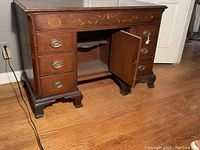 Front angle showing six drawers, central compartment with door open revealing an inner shelf and star inlay on back panel, brass drawer pulls and key lock on door