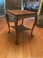 Side view of the antique tiger oak lamp table showing claw feet and curved legs.