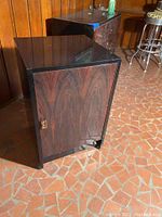 Black lacquer small single door cabinet angled showing wood grain door and brass handle