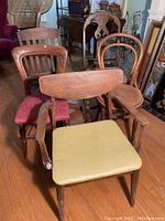 Seven vintage chairs grouped closely showing varying styles and upholstery.