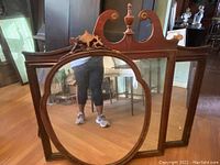 Front view of three vintage wooden framed mirrors showing large intact rectangular mirror and two smaller mirrors with decorative carved wood tops; visible damage on carved portions of smaller mirrors.