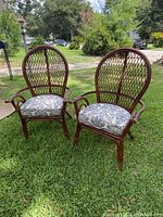 Front view of pair of bamboo chairs with lattice backs and patterned cushions on grass outdoors