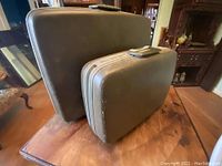 Two light brown Samsonite suitcases, one large and one smaller, stacked together showing their condition and details.