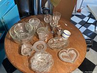 Full view of the lot showing mixing bowls, wine glasses, ramekins, and various cut glass serving pieces on a wooden table.
