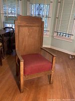 Front view of vintage oak high back pastoral chair with red upholstery showing wood frame and fabric seat and backrest
