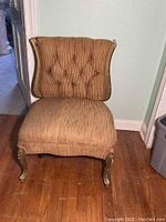 Front view of vintage slipper chair showing upholstered seat and button tufted back with carved wooden legs
