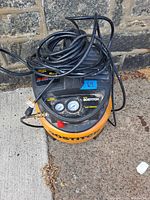 Top view of Bostitch air compressor showing gauges and power cord coiled on top.