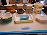 Wide view of the entire lot showing all 14 pieces including bowls and casseroles arranged on a table.