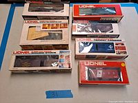 Group of 7 boxed Lionel train cars including Operating Giraffe, Rolling Stock, Freight Carrier, and caboose cars