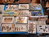Overhead image showing full lot of vintage military model kits including 13th Mountain Division, BMW R75, Corsair, Soviet Cavalry, and British Paratroopers.