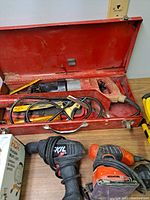 Photo showing Milwaukee Sawzall in red metal case with blades, Skil drill, Black & Decker sander and two work lights, one HDX portable work light in box and one yellow light.
