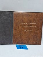 Photo of the booklet cover showing the title 'Official State Birds Of The United States Gold Stamp Series' embossed in gold on brown leather-like material.