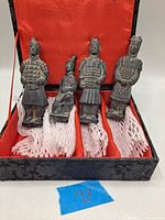 Four terra cotta Chinese warrior figurines displayed in original black box with red satin lining and white padding