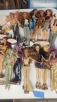 Top view of 14 dolls on table with stands and accessories