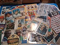 Wide shot of sports cards laid on blue surface, showing a variety of baseball and hockey cards, a 1993 Phillies World Series pin and some collectibles