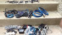 Various cords and cables arranged on steps, including black power cords, blue and black HDMI/audio cables, and various other cables.