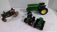 Four die cast tractor models of varying sizes arranged together with visible wear and rust.