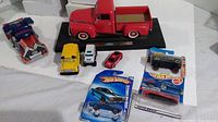 Full view of the lot showing all 8 vehicles including the red 1948 Ford F-1 pickup on display base, loose vehicles, and three Hot Wheels cars in packaging.
