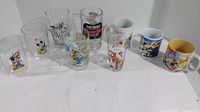 Photo showing the full set including 3 Disney-themed ceramic mugs and 6 Disney-themed clear glasses, featuring characters like Mickey Mouse, Donald Duck, Pluto, Big Bad Wolf, and Walt Disney's Pseudopia ads.