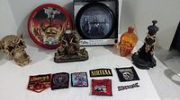 Full view of lot including two clocks, multiple band patches, and skull-themed candle holders and decorative items.