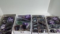 Four boxes filled with assorted new sunglasses in original packaging, with purple Hollywood price tags.