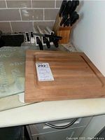 Wood cutting board showing smooth surface with groove and knife slots on underside.