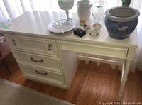 White painted desk with four drawers and brass hardware, decorative drawer front details, photographed from front and side angles.