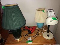 Photo showing all four items on wooden table: two table lamps, one desk lamp, and Clairol blow dryer.