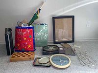 Photo showing assorted items including gift bags, picture frames, clocks, chess set laid on floor with white background