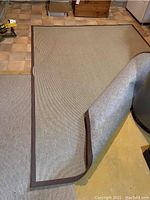 Rug laid out showing the top side and one corner lifted to reveal the back side