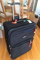 Front view of black Air Canada suitcase with extendable handle and orange zipper pulls