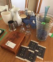 Full lot view showing vases, candle holders, pewter mug, candy dishes, Bible box, and coasters on wooden table.