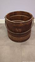 Front view of antique wooden sugar barrel showing the circular shape, metal bands and handle