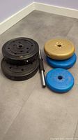 Photo showing all barbell weights stacked with the small barbell handle alongside.