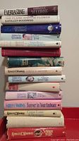 Stack of 13 hardcover romance books primarily by Kathleen E. Woodiwiss with visible titles such as Everlasting, The Flame and the Flower, A Rose in Winter, and Forever in Your Embrace.
