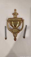 Front view of brass door knocker showing 'Our Home', year 1991, and included mounting bolts.