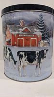 Front side view of round tin showing black and white cows standing in snow with red barn labeled Silver Tree Farm in background